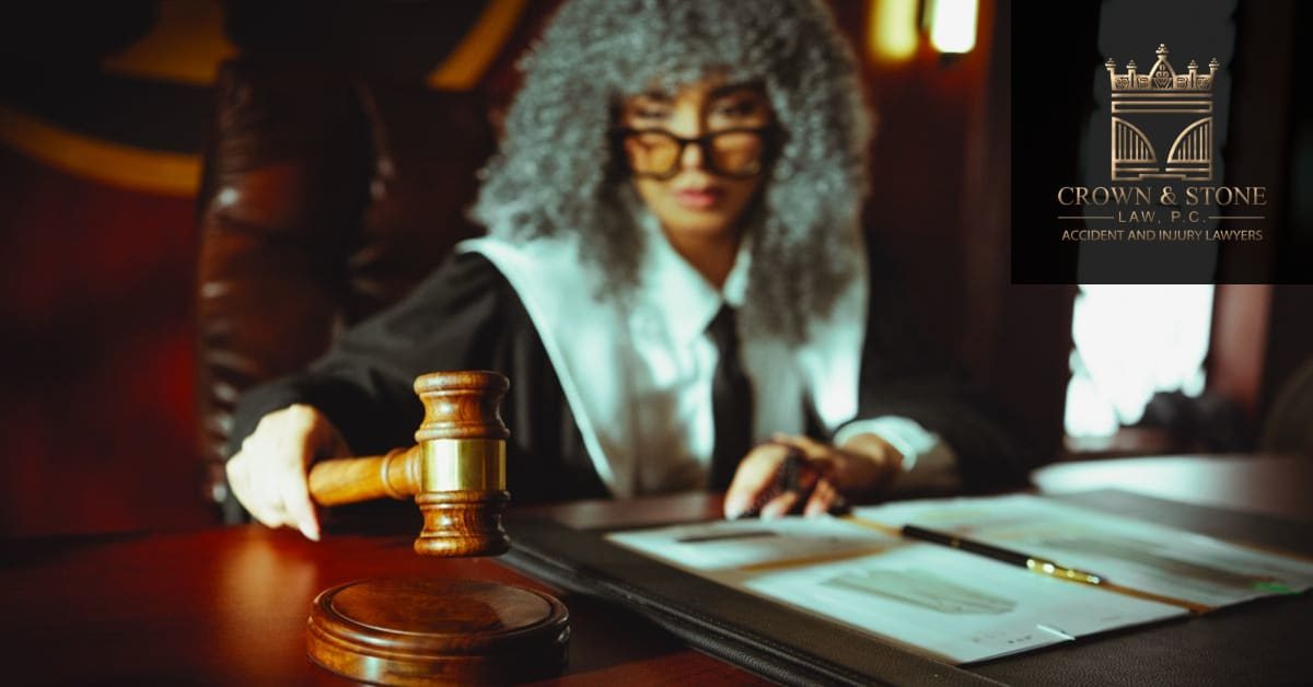 A wooden gavel resting on legal documents on a desk, representing a California pain and suffering settlement claim. Branded with the Crown & Stone Law, P.C. logo.
